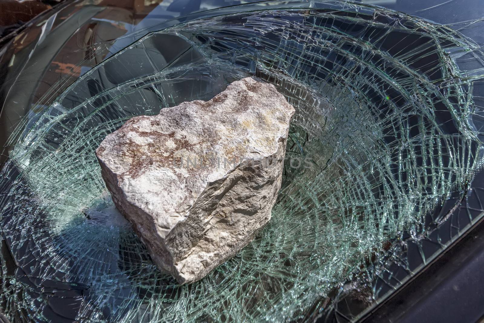 broken car windshield with a huge stone
