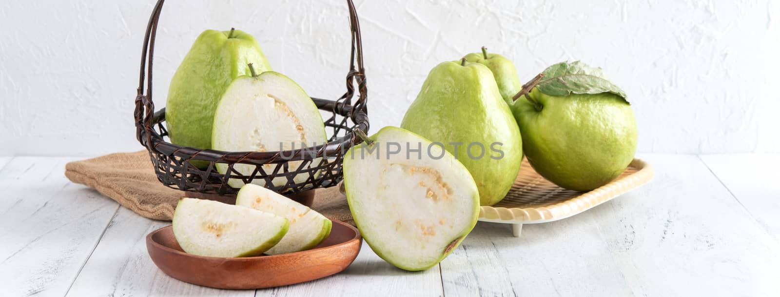 Delicious beautiful guava set with fresh leaves isolated on bright white wooden table background, close up.
