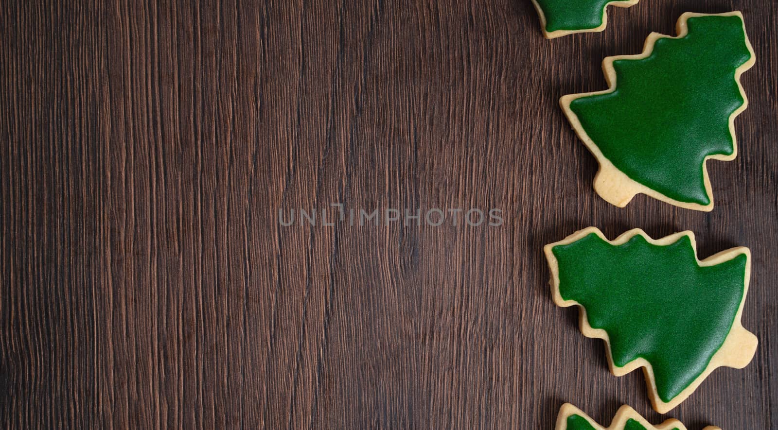 Top view of decorated green plain flavor gingerbread Christmas tree cookie on wooden table background with copy space, concept of holiday celebration.