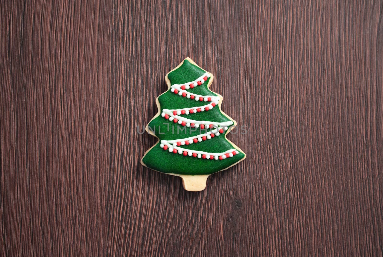 Top view of decorated green plain flavor gingerbread Christmas tree cookie on wooden table background with copy space, concept of holiday celebration.