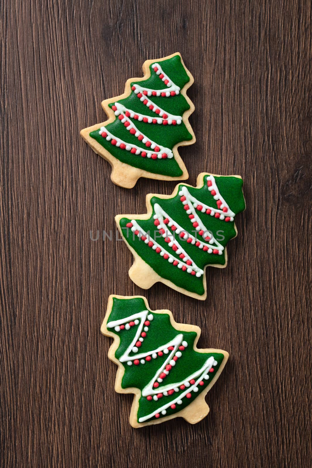 Top view of decorated green plain flavor gingerbread Christmas tree cookie on wooden table background with copy space, concept of holiday celebration.