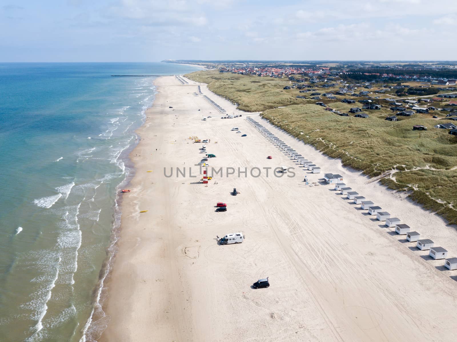 Lokken, Denmark - July 18, 2019: Aerial drone view of Lokken Beach with cars and beach huts.