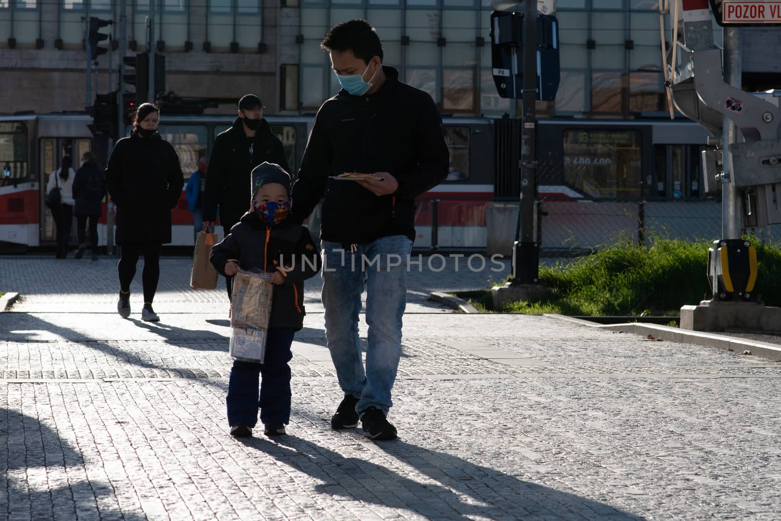 People on a sunny winter day during coronavirus. They are walking or doing some sports or having a time relax at Hradcanska metro stop in Prague. by gonzalobell