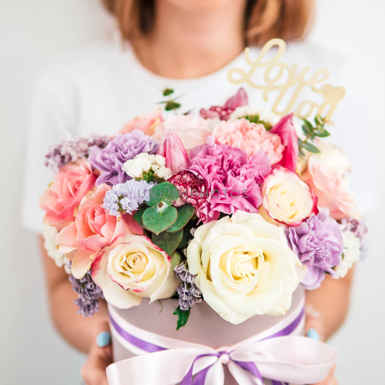 Beautiful bouquet with different flowers in woman hands. Bouquet with roses, dianthus, carnation bush, limonium, lilac and tulip. Shallow DOF, copy space. Top view. Square format for social media