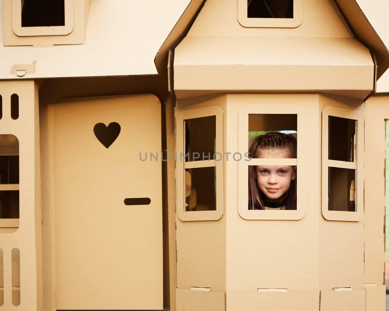 Child playing in a cardboard playhouse. Eco concept.