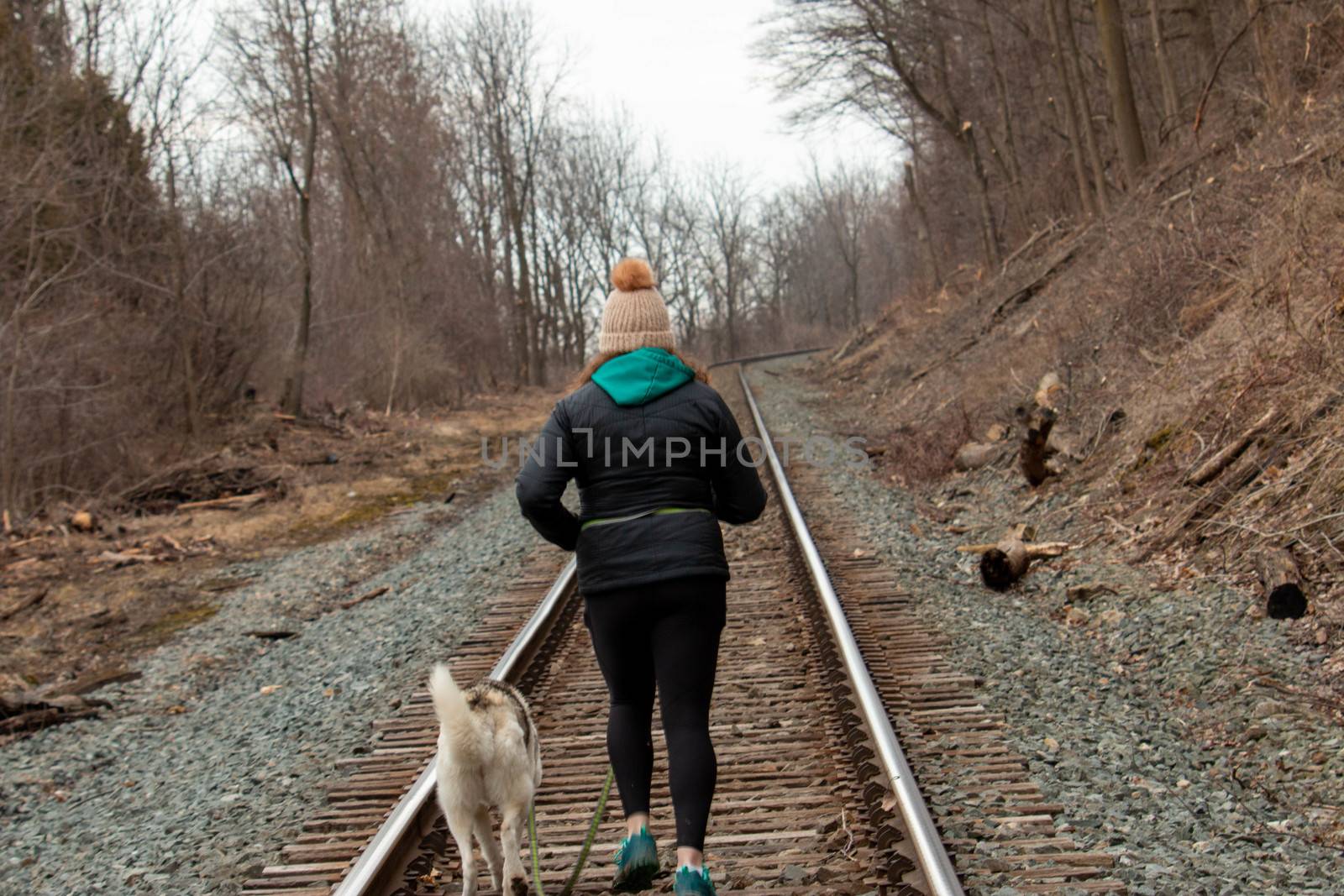 Hamilton Ontario, March 24 2020: Editorial photo of a women walking on train tracks with her dog. Editorial theme of loneliness by mynewturtle1