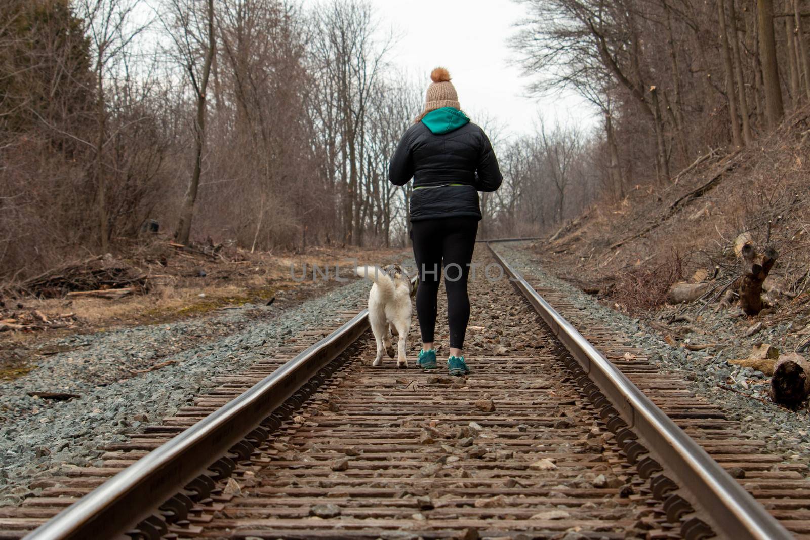 Hamilton Ontario, March 24 2020: Editorial photo of a women walking on train tracks with her dog. Editorial theme of loneliness by mynewturtle1