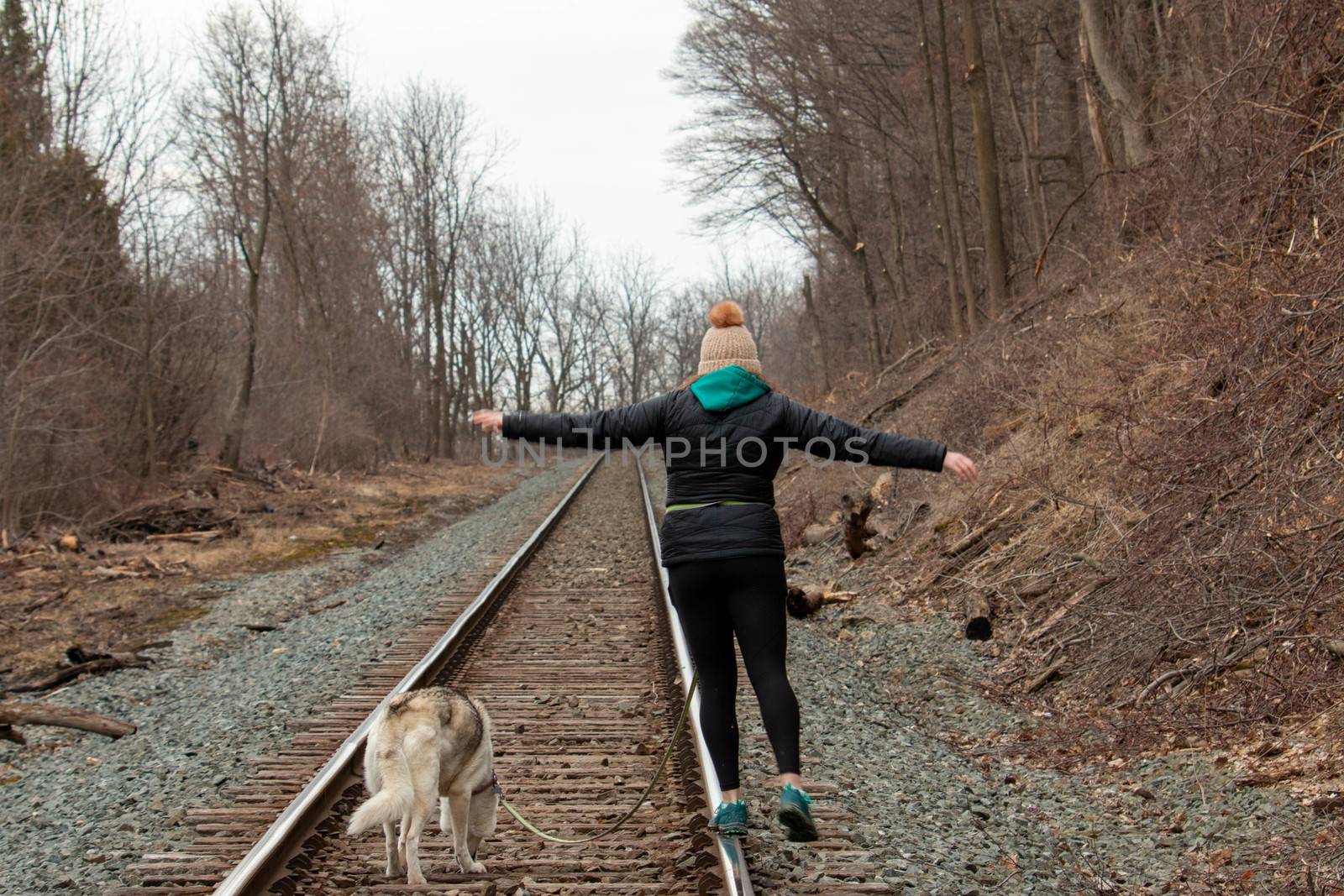 Hamilton Ontario, March 24 2020: Editorial photo of a women walking on train tracks with her dog. Editorial theme of loneliness . High quality photo