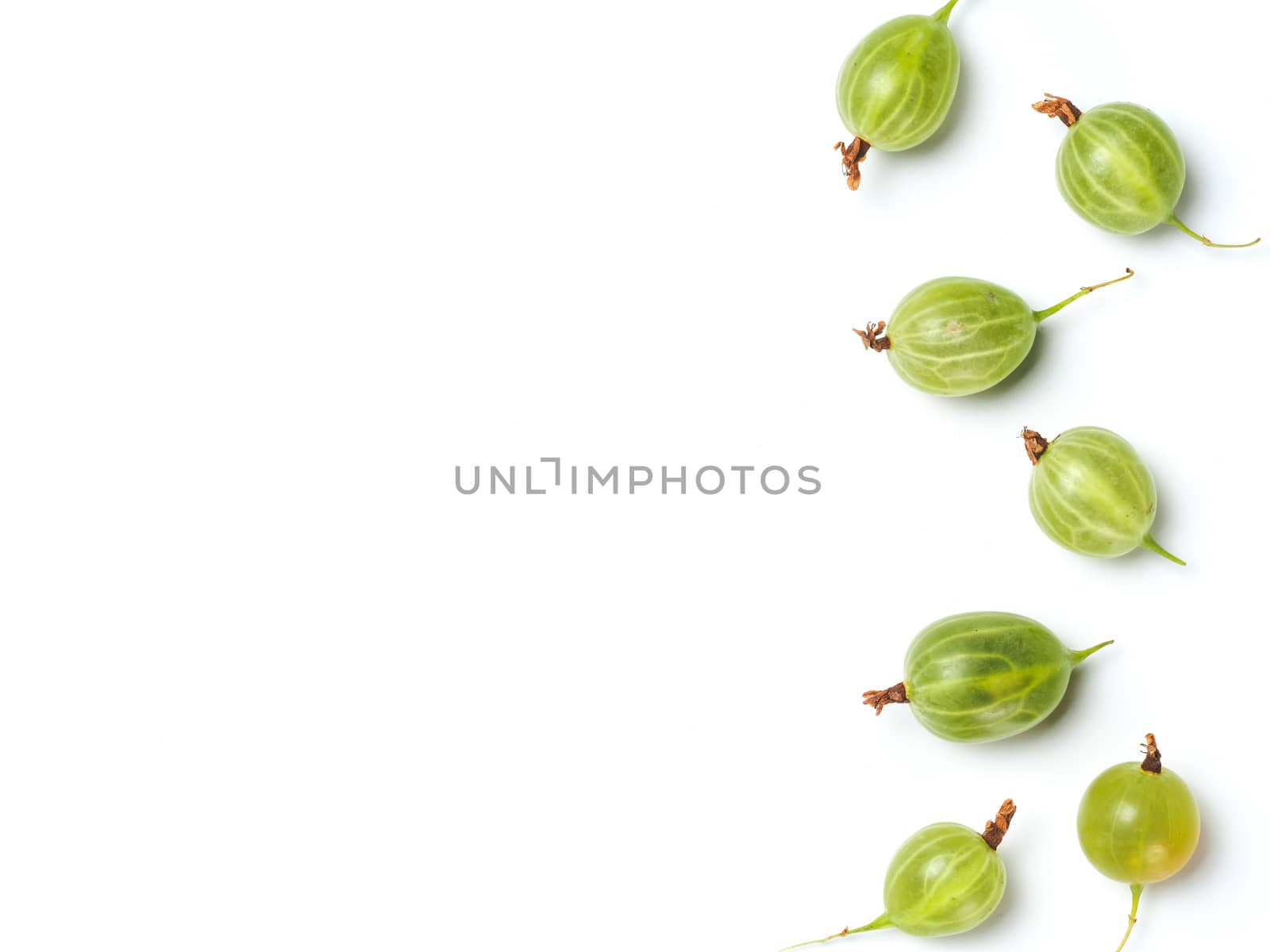 Heap of ripe green gooseberry berries on white background. Creative layout made of organic gooseberries. Isolated on white with clipping path. Top view or flat lay. Copy space for text. Food concept.