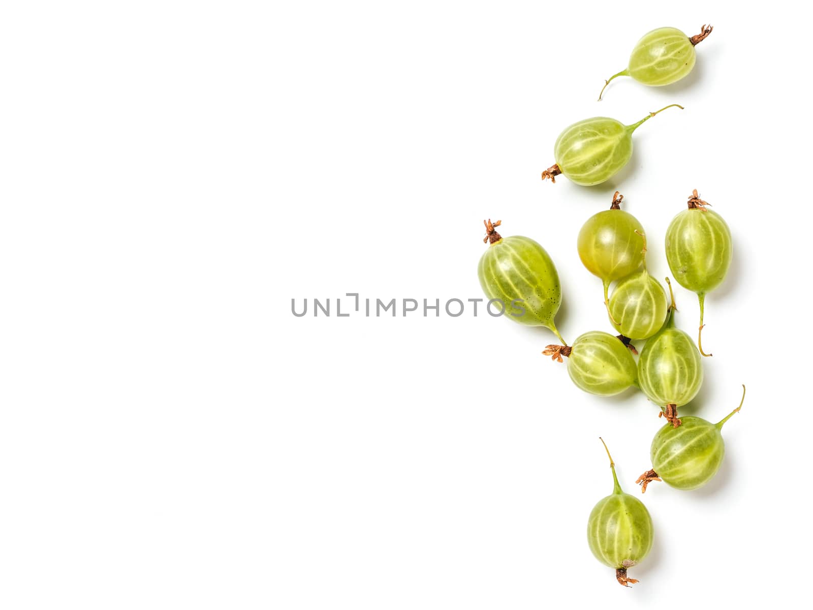 Heap of ripe green gooseberry berries on white background. Creative layout made of organic gooseberries. Isolated on white with clipping path. Top view or flat lay. Copy space for text. Food concept.