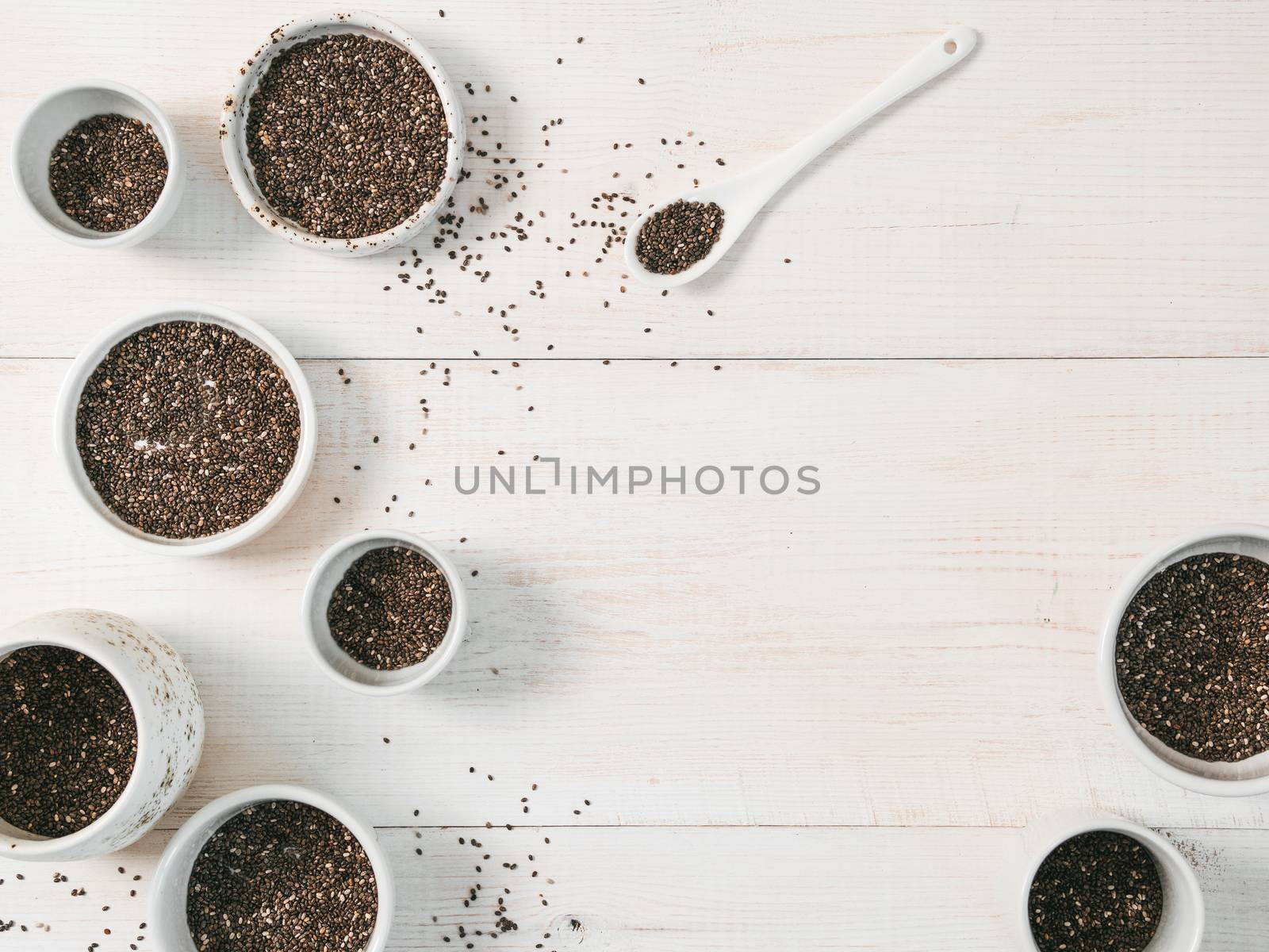 Organic chia seeds on white wooden table. Set of small bowls with organic chia seed. Superfood concept. Copy space. Top view or flat-lay.