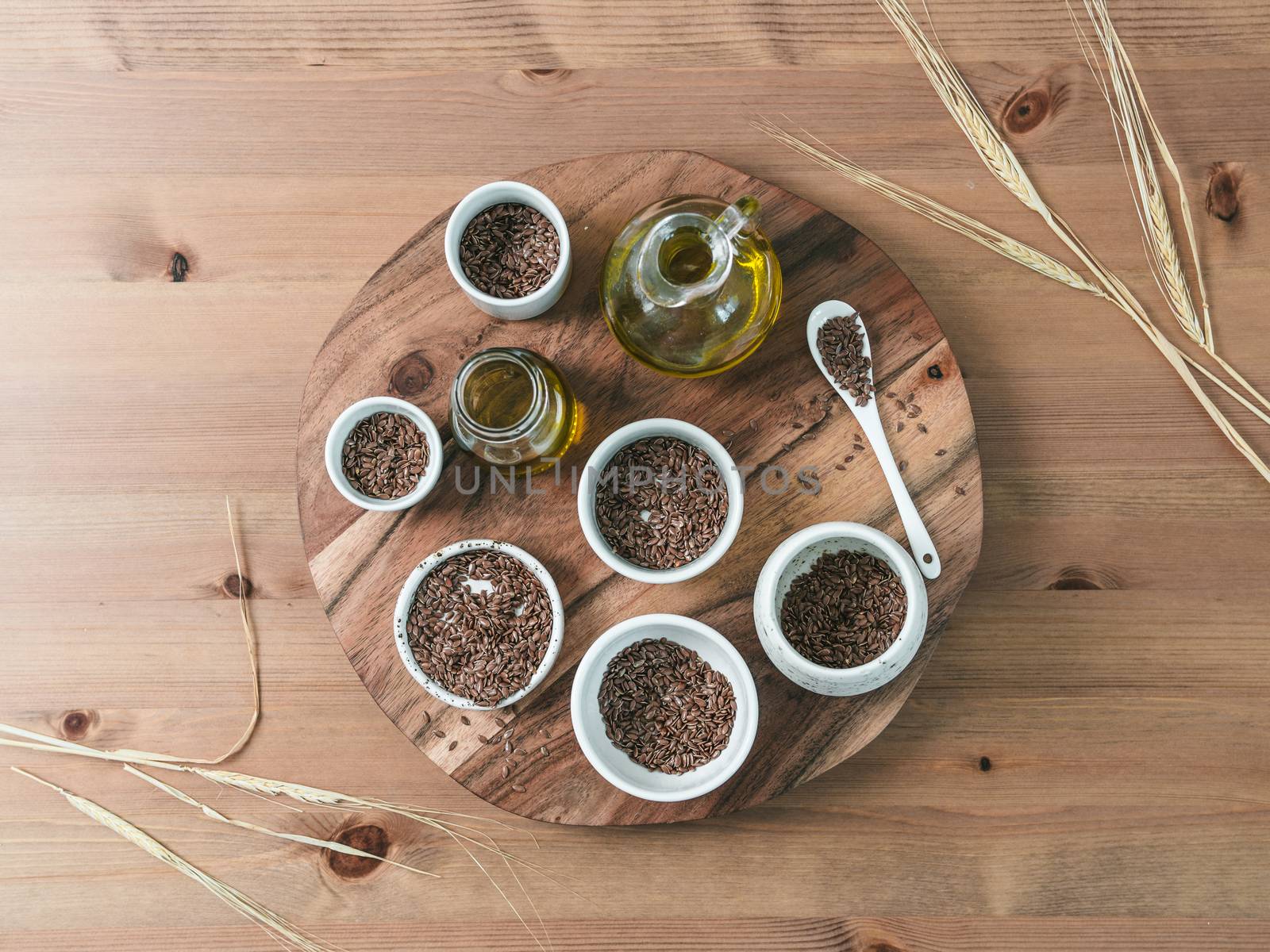 flax seeds and flaxseed oil on wooden table. Set of small bowls with organic flax seed or linen seed. Flax oil is rich in omega-3 fatty acid. Copy space. Top view or flat-lay.