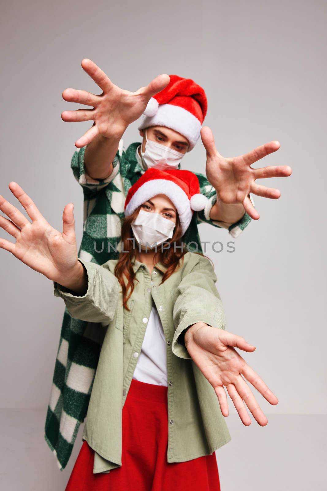 Cheerful young couple in medical masks Christmas life with hands together New Year by SHOTPRIME