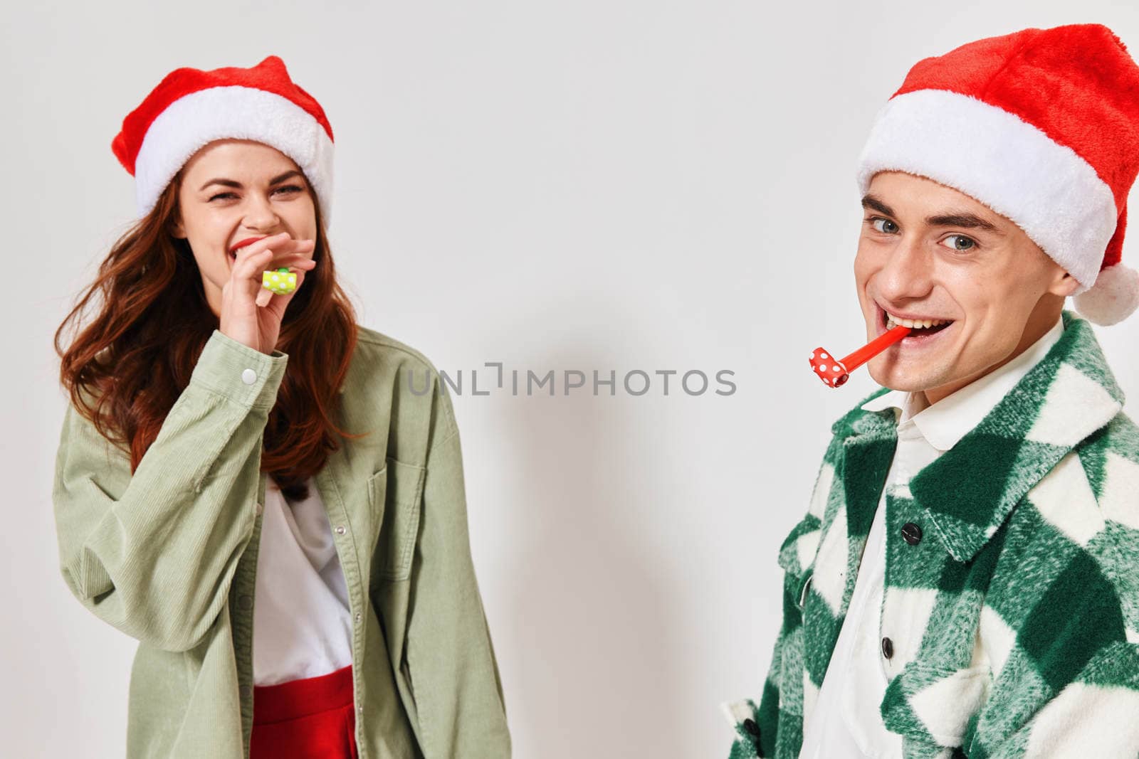 Cheerful man and woman festive pipes Christmas New Year hats fun. High quality photo