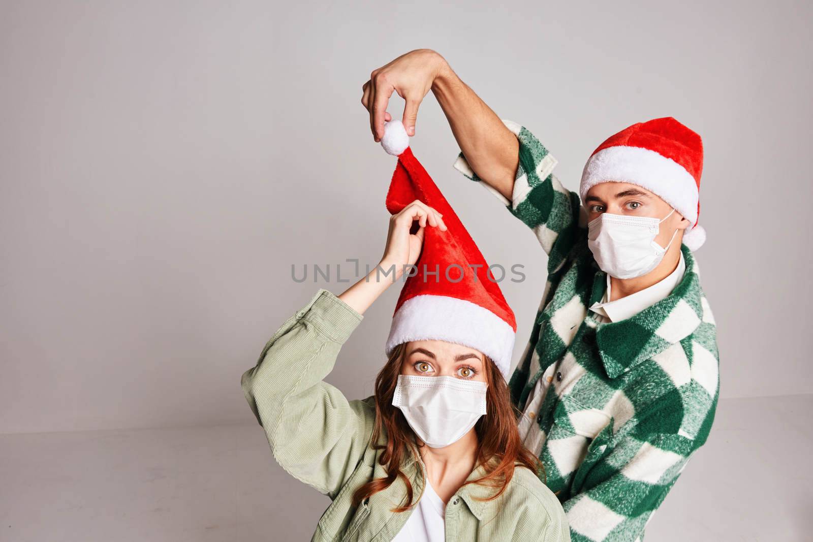 Young couple of Christmas hats Christmas winter fun medical masks on face. High quality photo