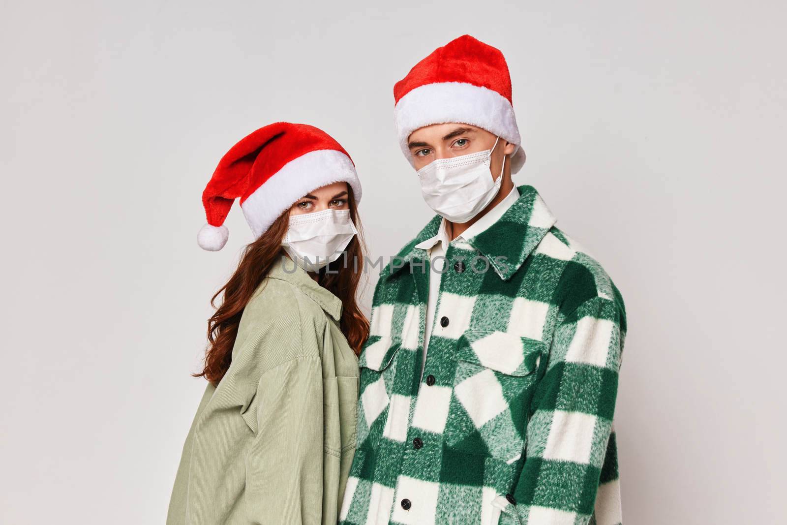 Man and woman in medical masks Christmas hats holiday gray background by SHOTPRIME