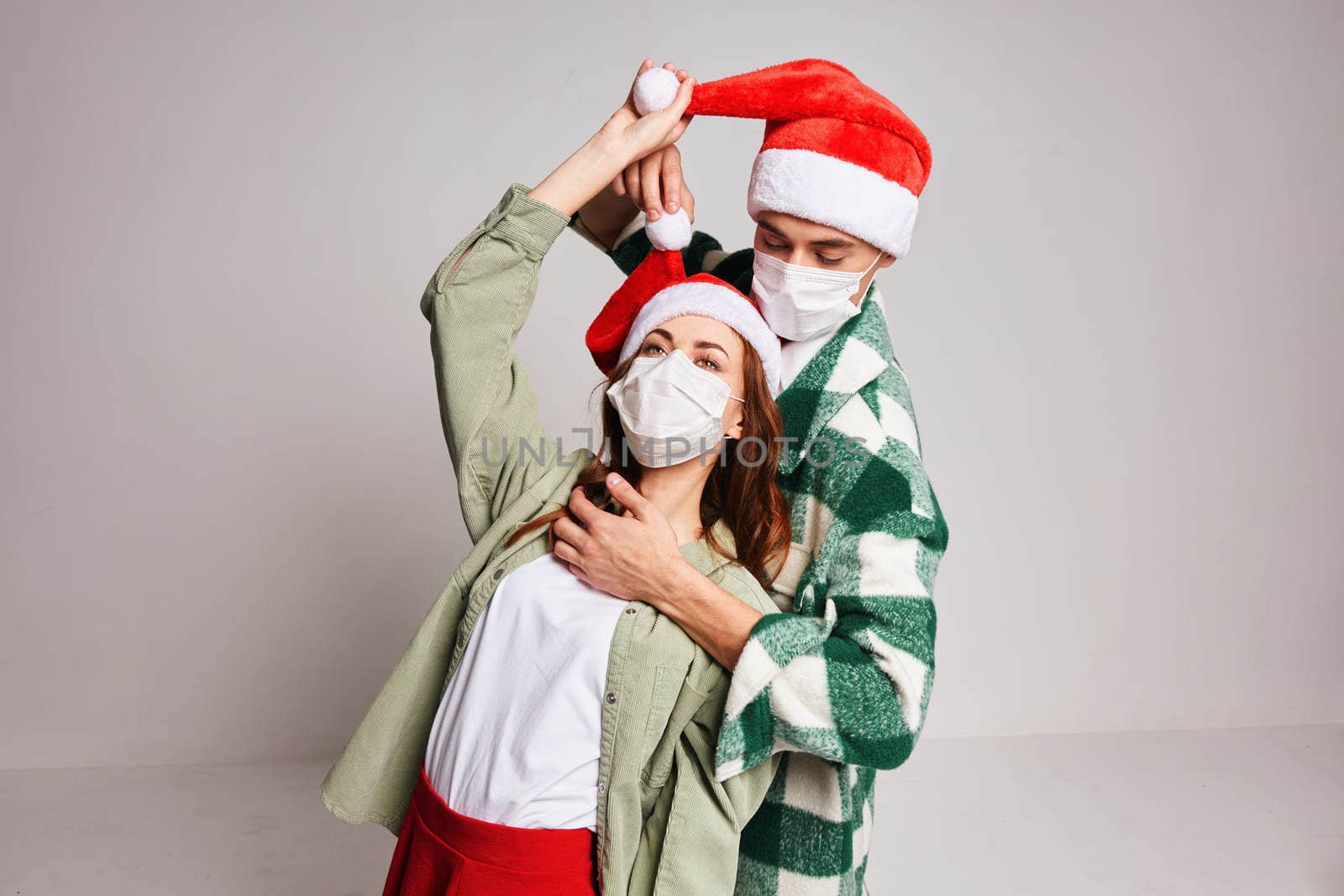 Man and woman embrace fun and holiday medical New Year masks. High quality photo