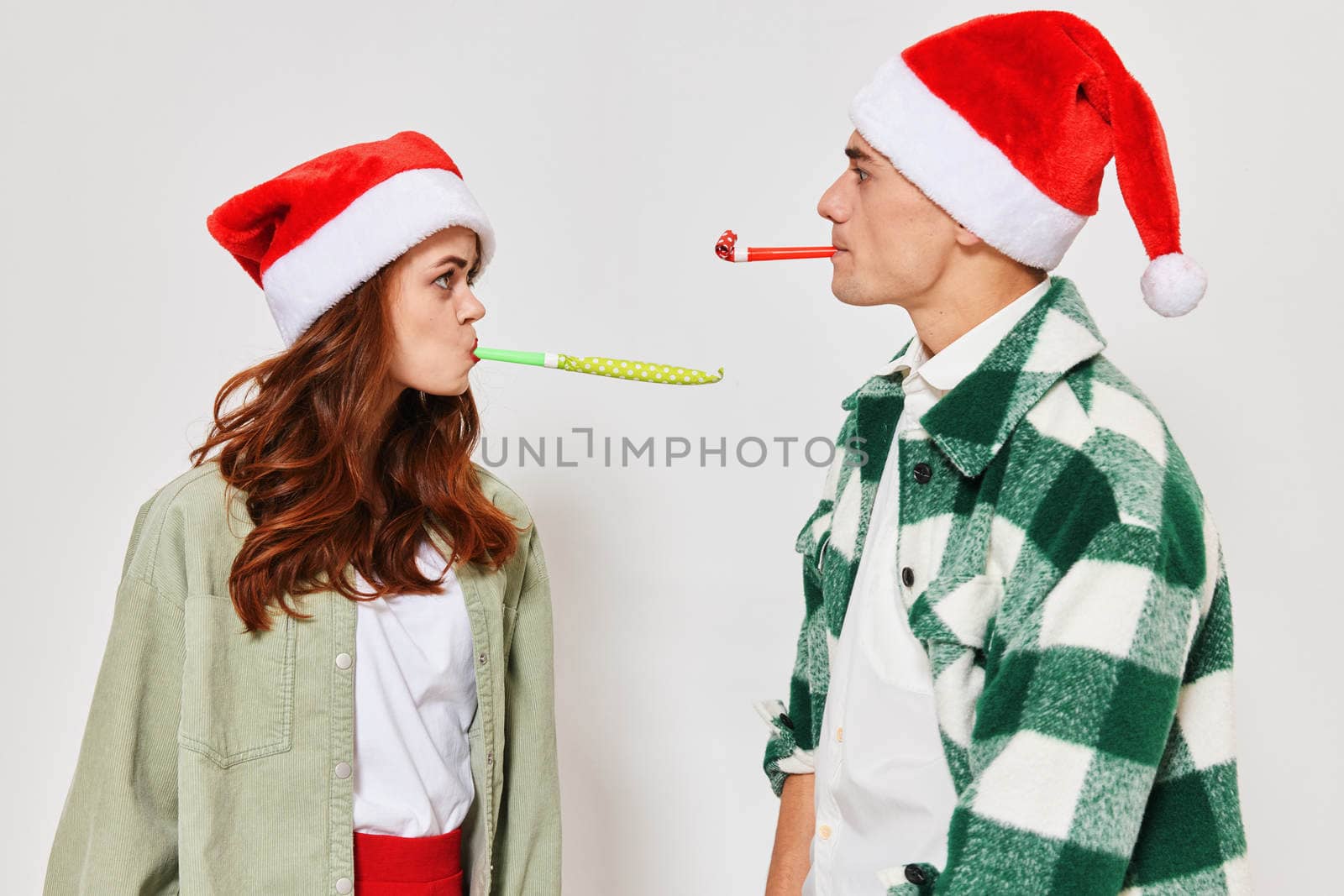 Man and woman in New Year's Santa hats festive pipes fun young couple. High quality photo