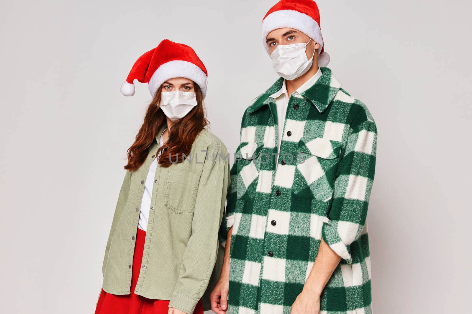 Man and woman stand next to medical masks New Years Eve Christmas holiday studio by SHOTPRIME