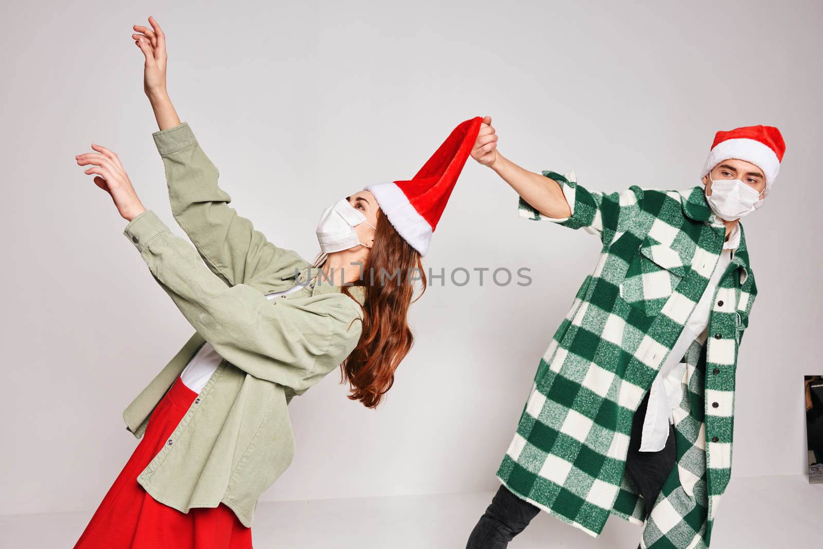 young couple celebrate Christmas together in santa hat emotions medical masks on face by SHOTPRIME