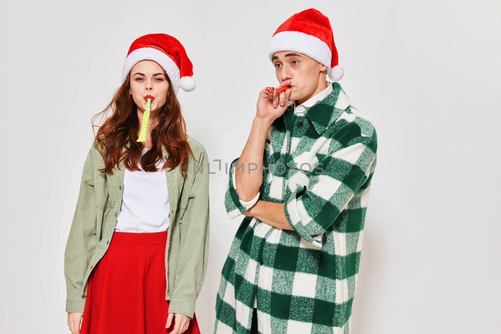 cheerful young couple wearing new year's clothes festive pipes mood. High quality photo