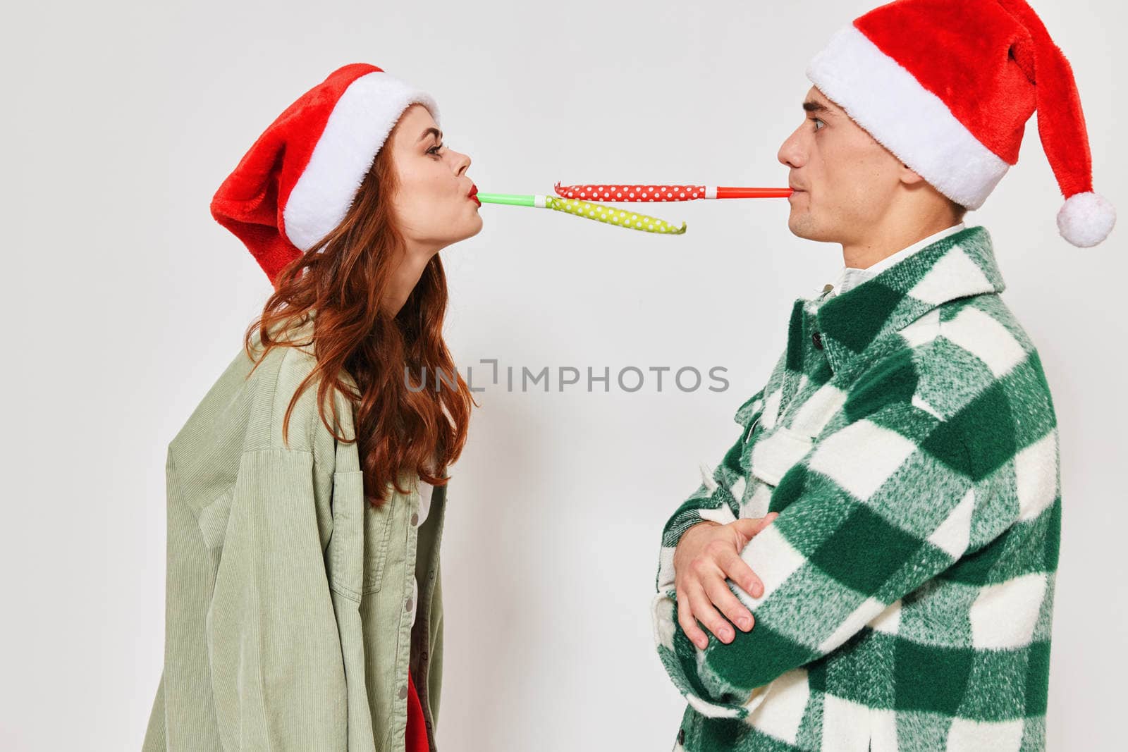 cute young couple in christmas hats multicolored pipes fun together holiday. High quality photo