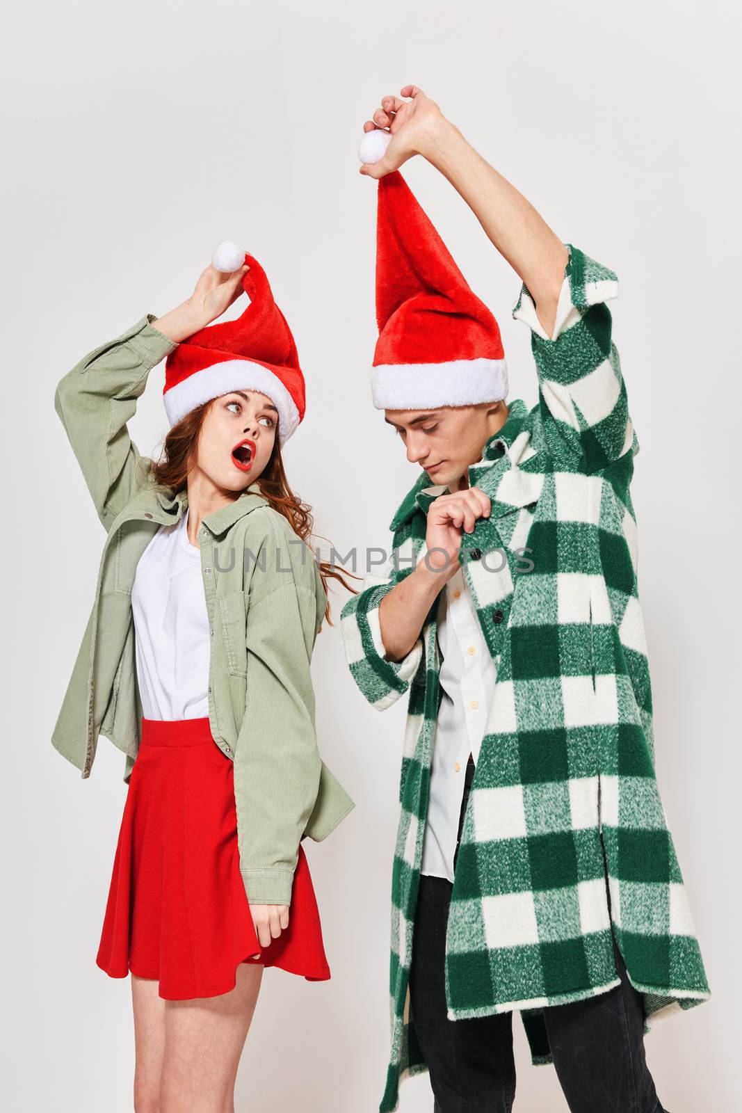 cheerful man and woman in Christmas hats holiday New Years relationship fun by SHOTPRIME