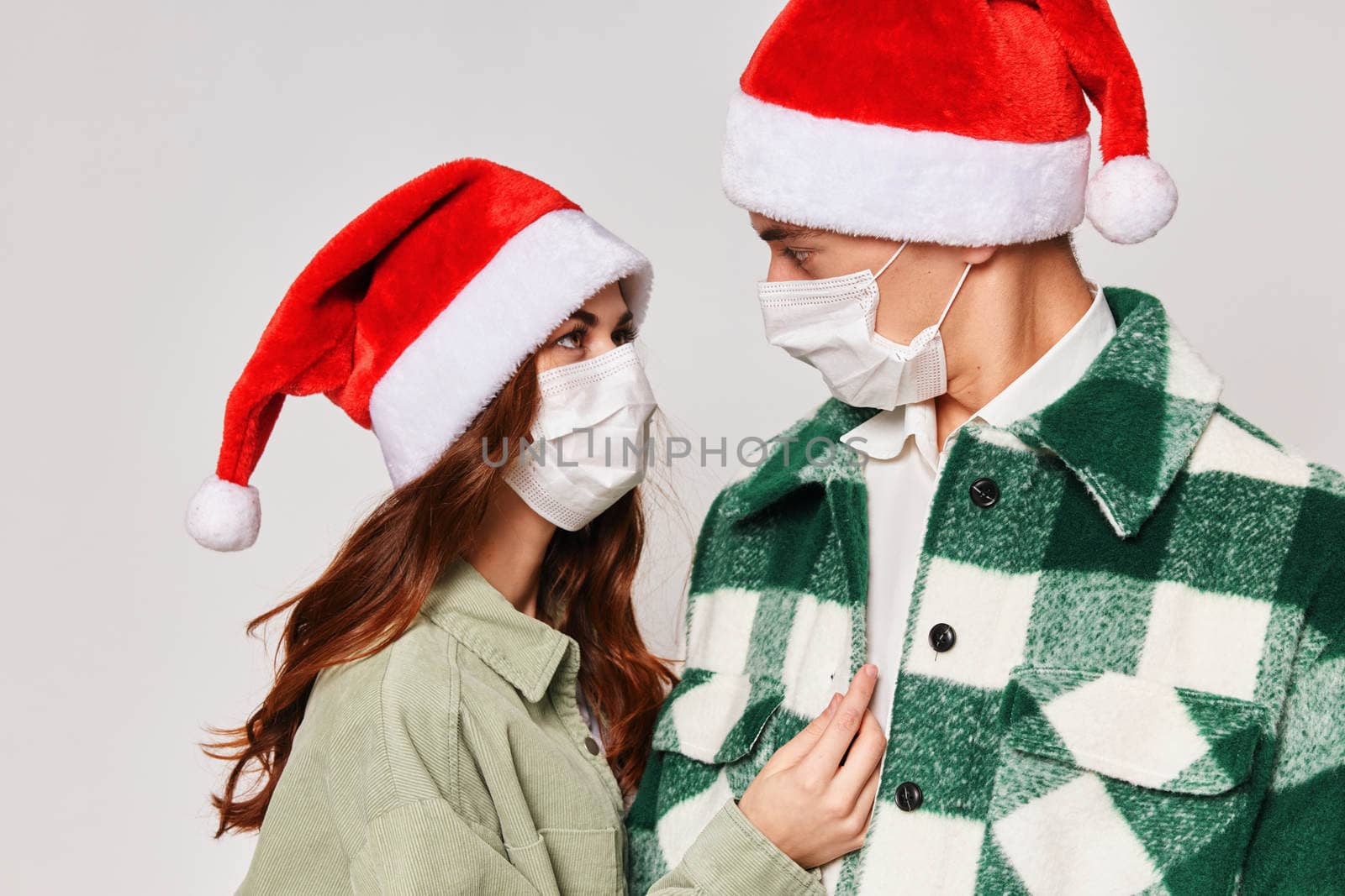Cute young couple christmas hats medical masks close-up hug. High quality photo