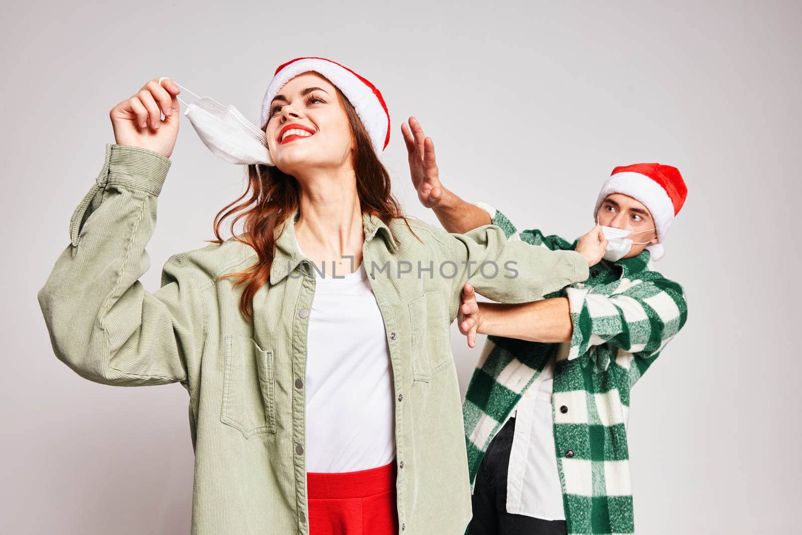 man and woman wearing christmas hats fun together holiday medical masks. High quality photo