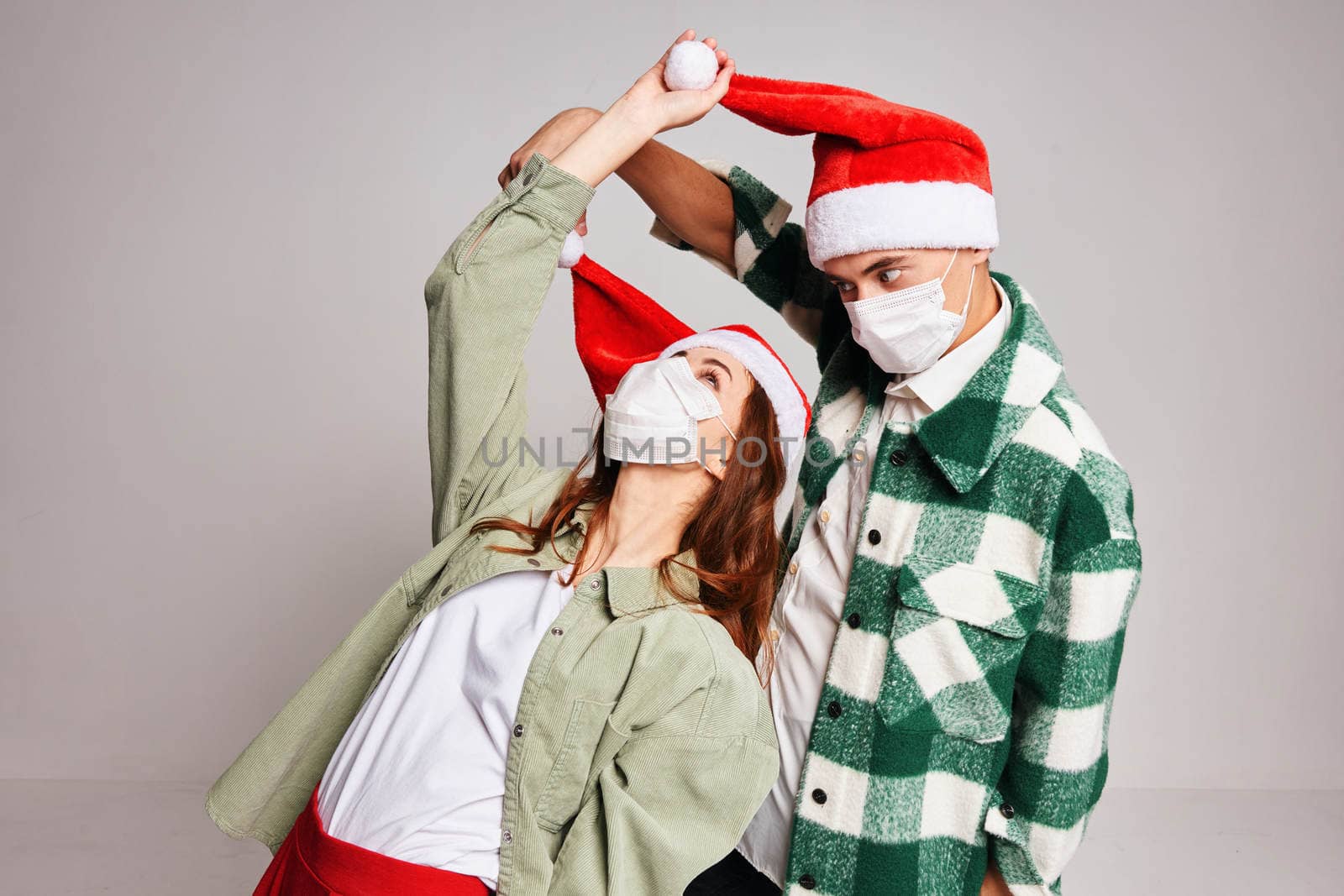 young couple face mask santa hats fun holiday christmas eve by SHOTPRIME
