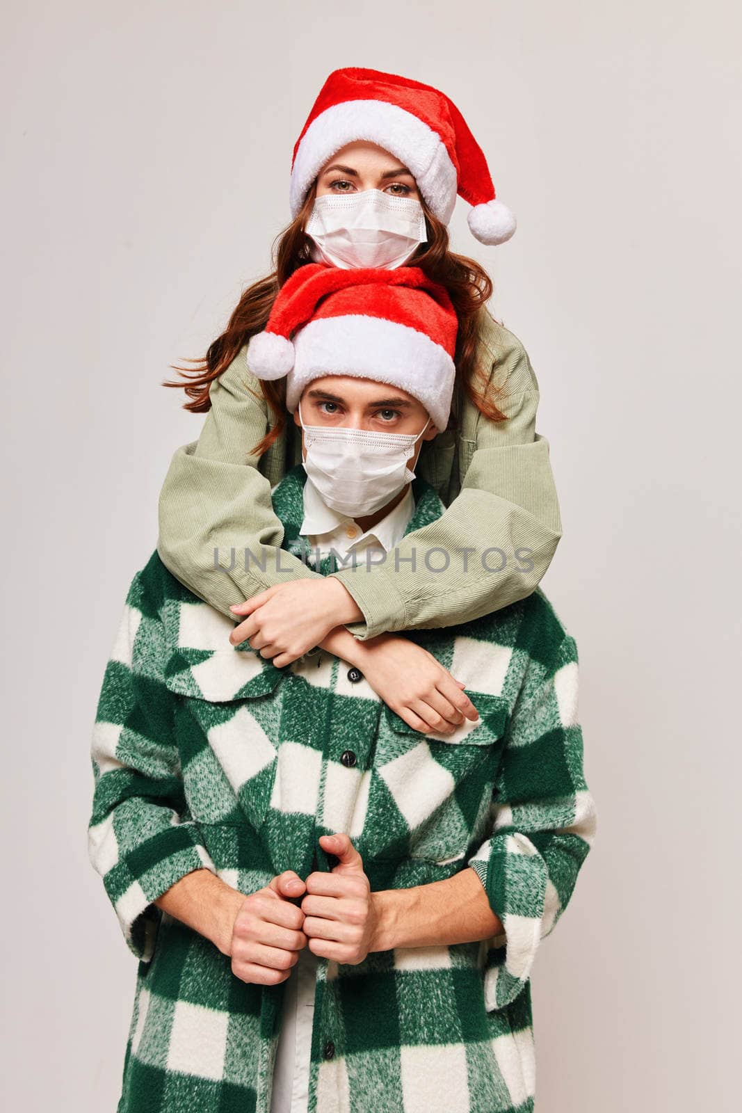 Young couple in medical masks Christmas holiday embrace. High quality photo