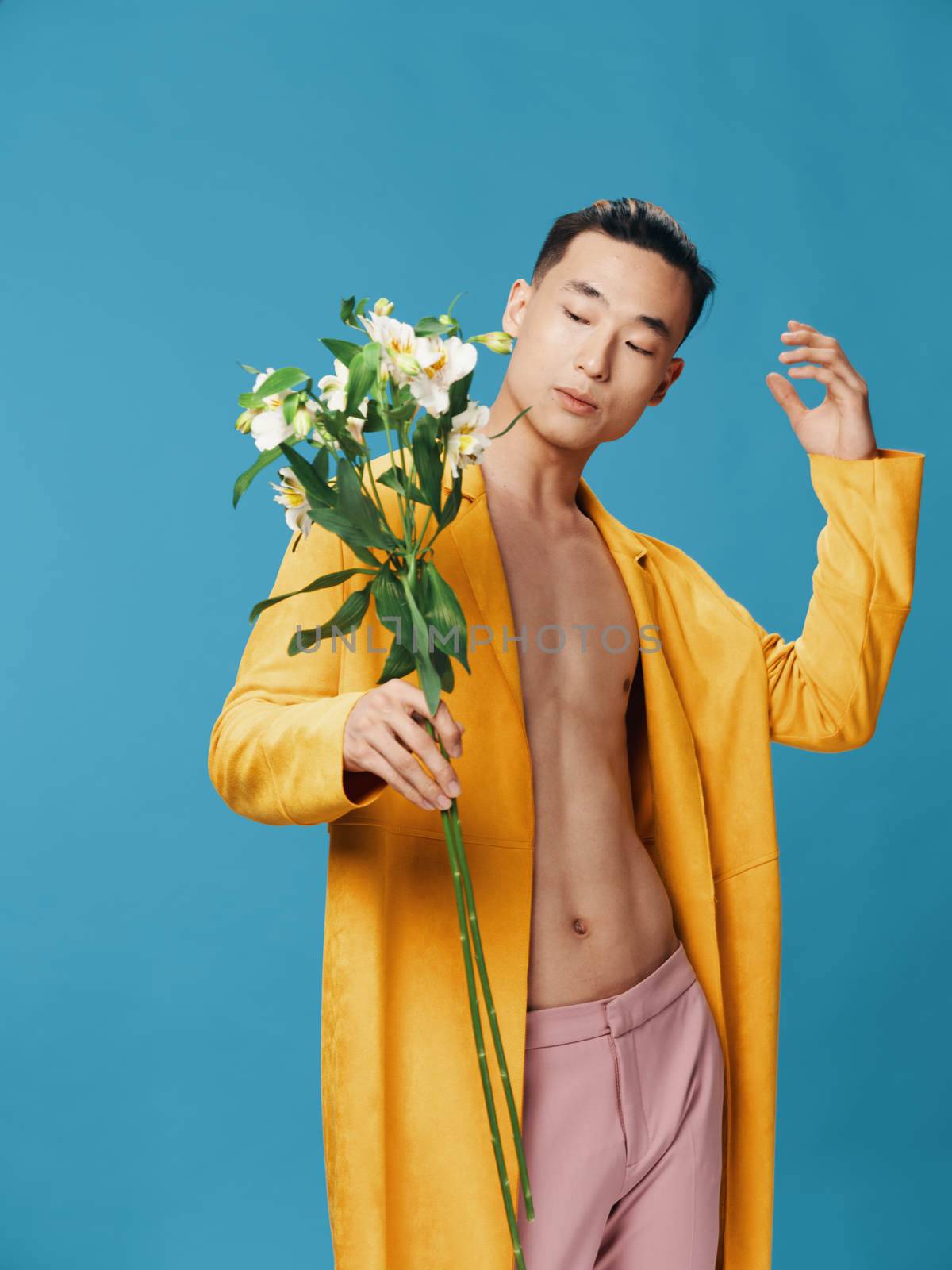 Asian man bouquet of white flowers yellow coat blue background Copy Space. High quality photo