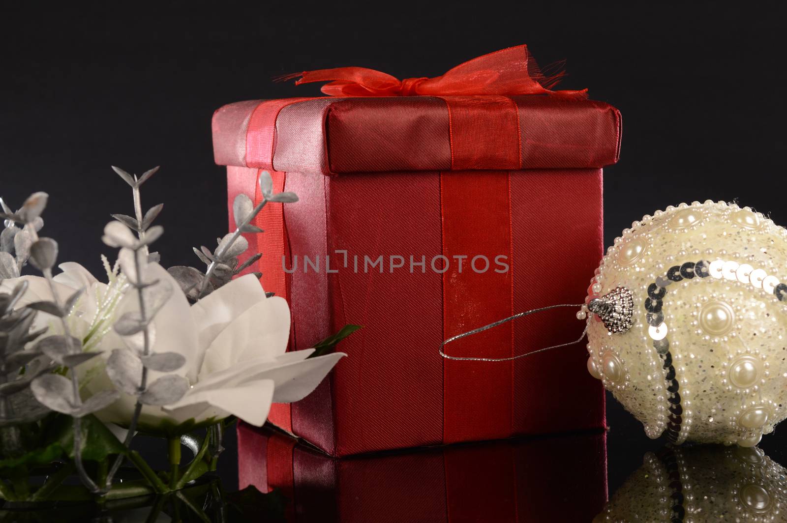 A closeup image of a red Christmas gift with decorative items to compliament the festive season.