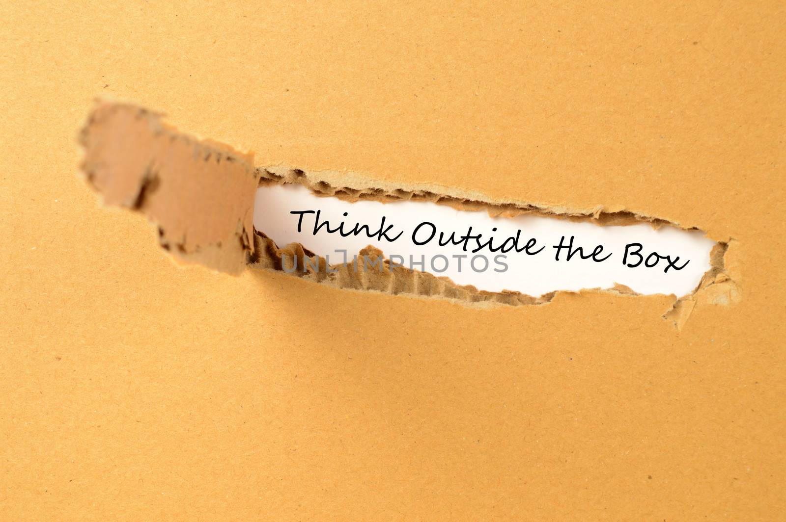 A conceptual image with text revealed from a tear in cardboard saying to think outside the box.