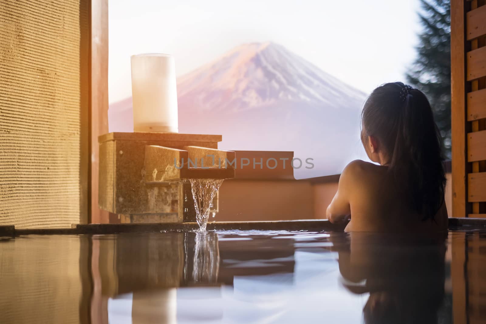 Beautiful woman enjoy onsen (mineral hot bath) in morning and seeing view of Fuji mountain in japan by Surasak