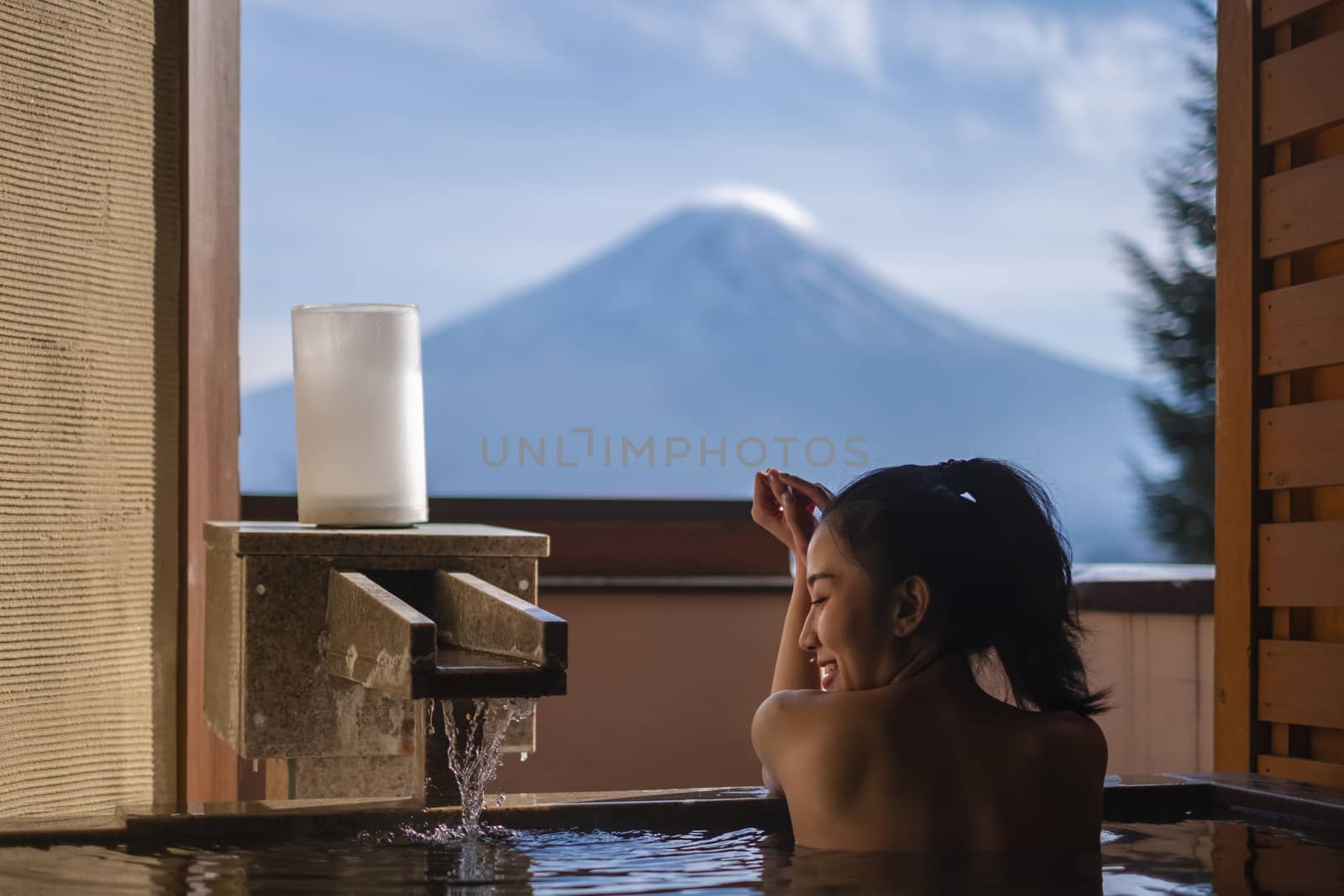 Beautiful woman enjoy onsen (mineral hot bath) in morning and seeing view of Fuji mountain in japan 