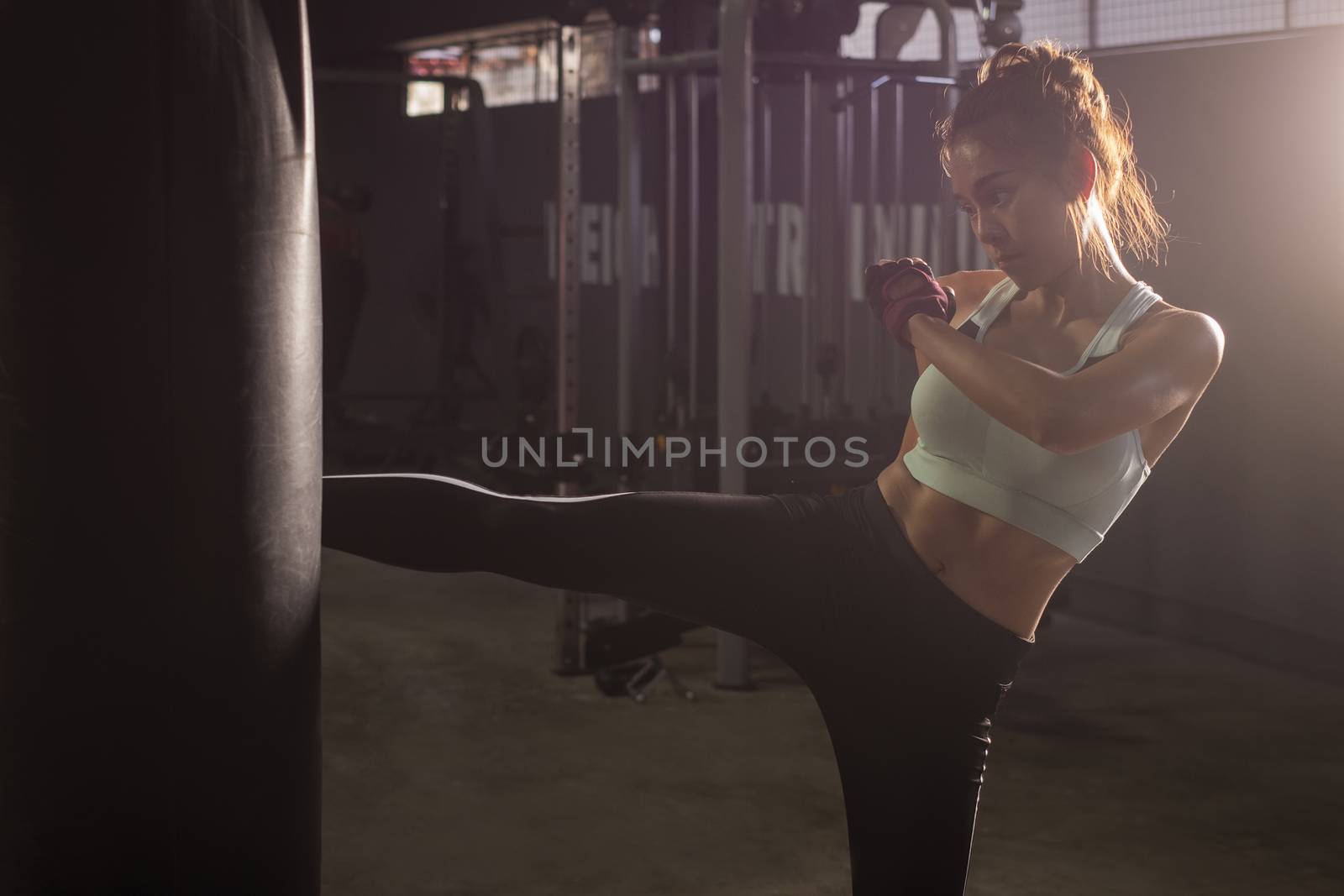 Fitness girl doing kick boxing training in sport gym by Surasak