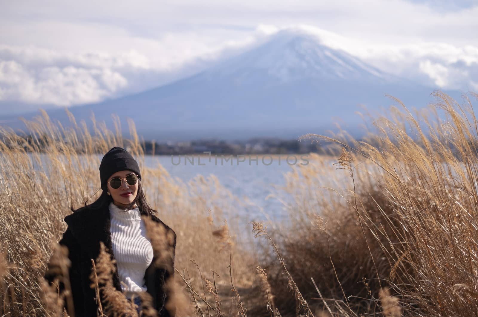 Beautiful smiling woman tourists are traveling and feel happy with Mt Fuji in the morning on the lake kawaguchiko, Japan