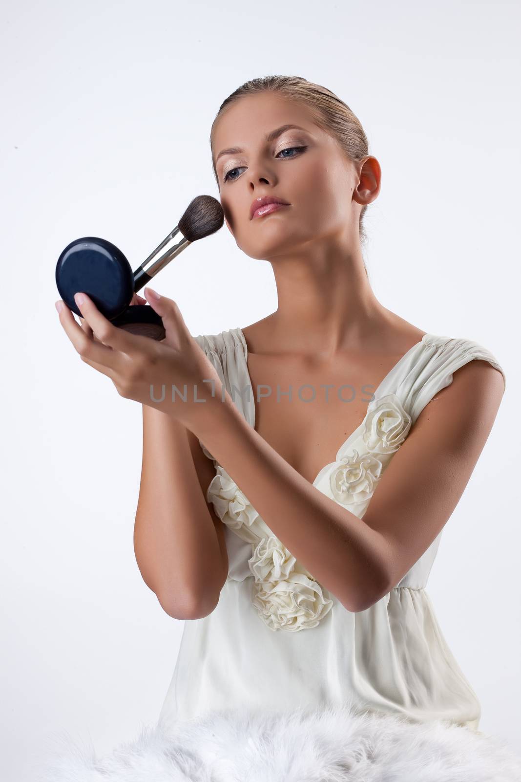 Young Woman Applying Cosmetics by Fotoskat