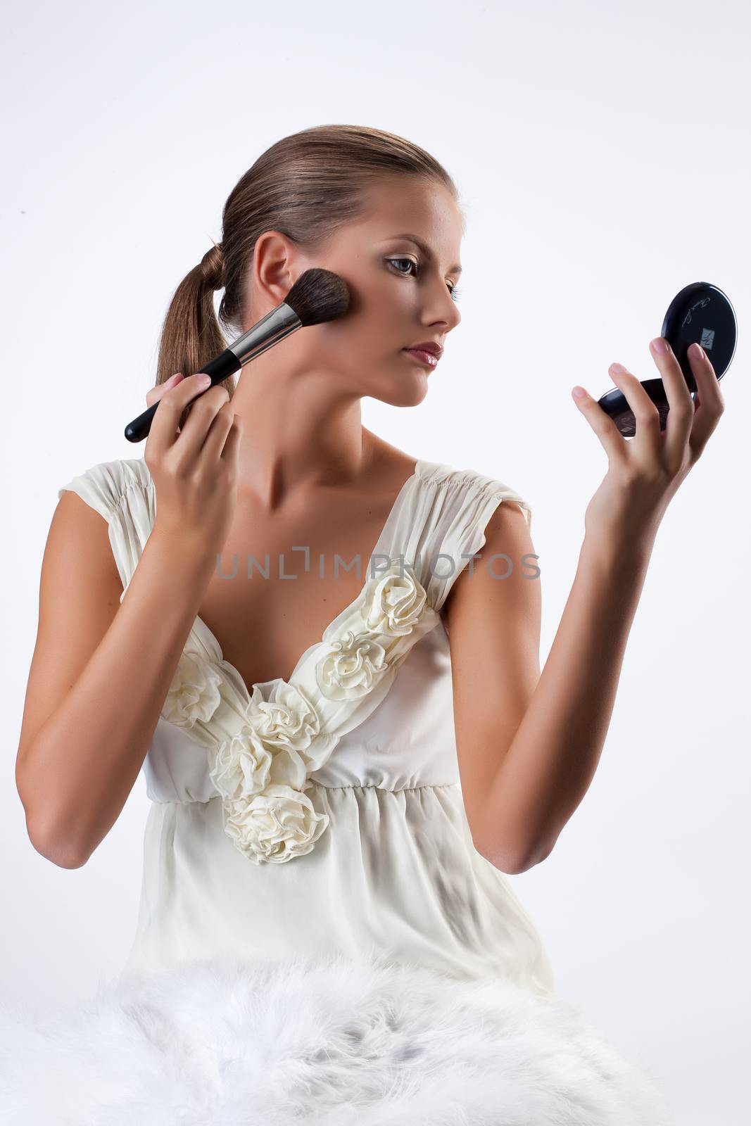 Young Woman Applying Cosmetics by Fotoskat