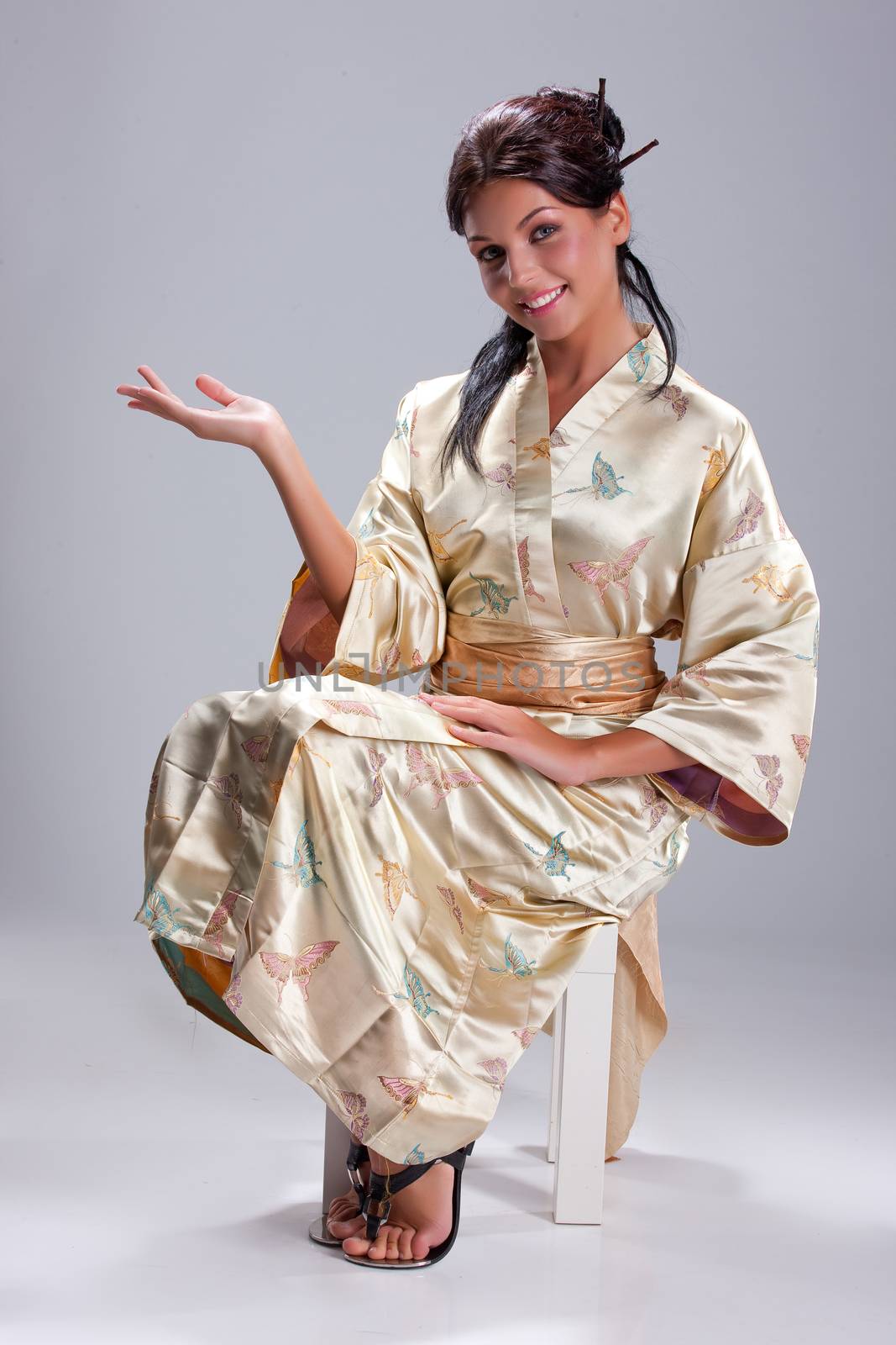 Young beautiful woman in japanese national clothing on an isolated studio background