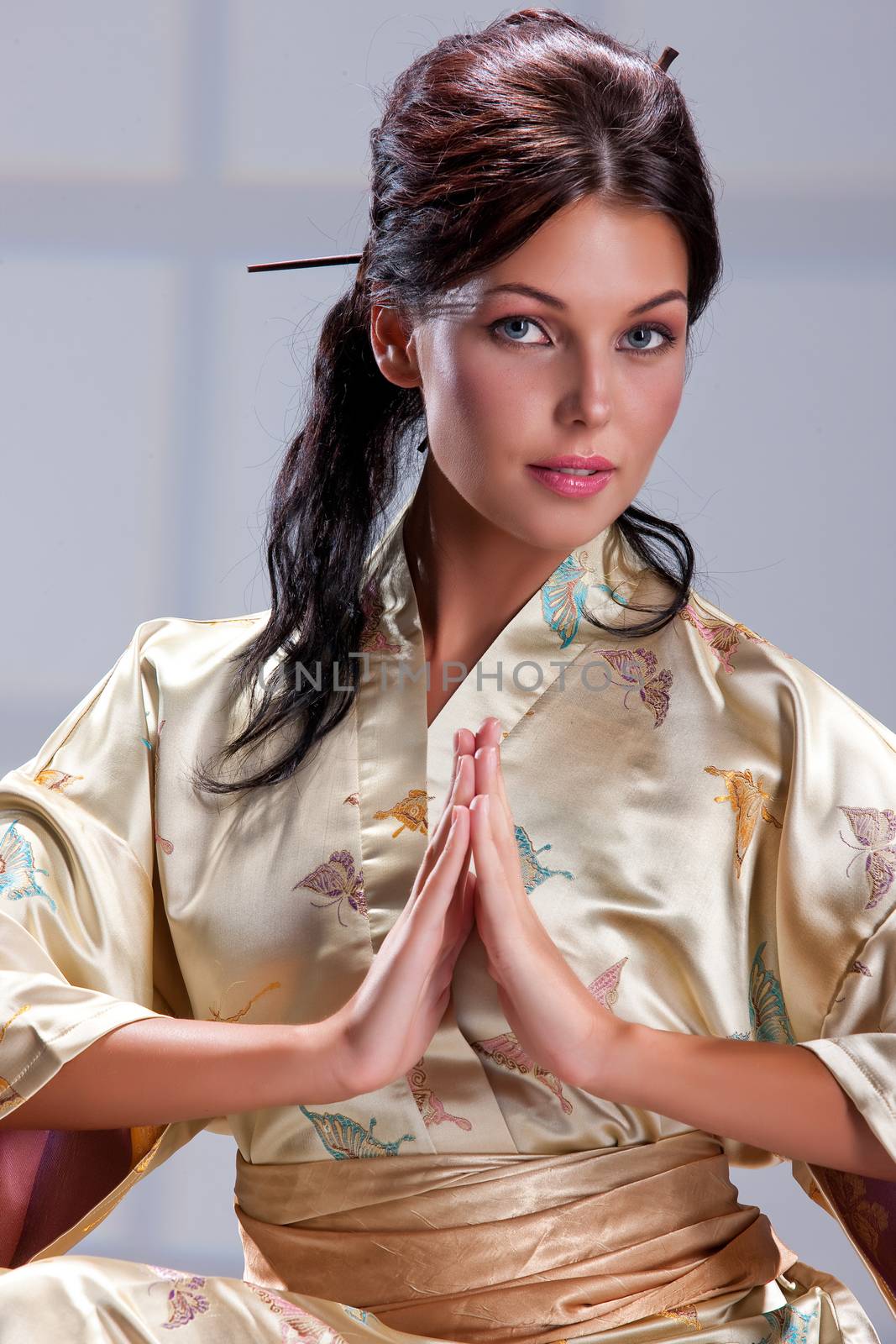 Young beautiful woman in japanese national clothing on an isolated studio background