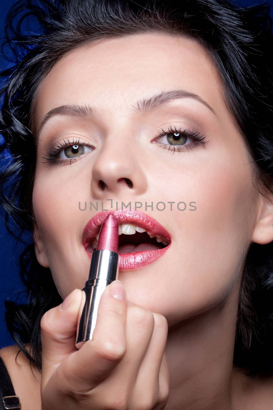 Young beautiful woman applying cosmetics onto her face