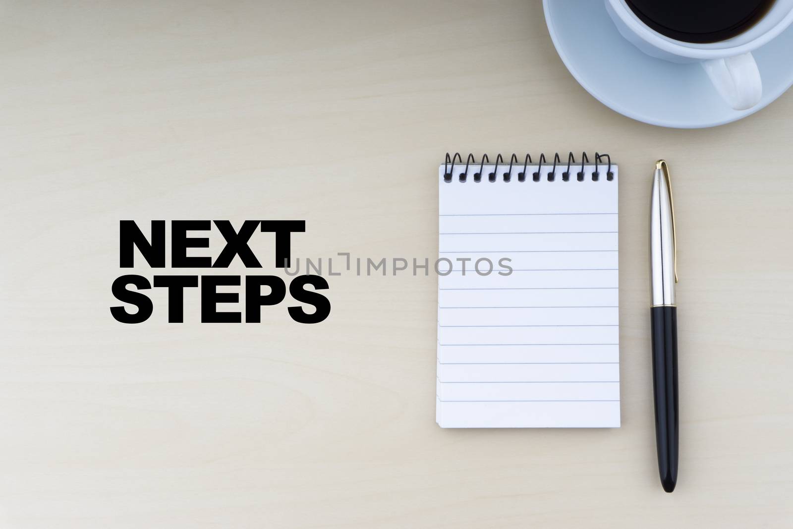 NEXT STEPS text with fountain pen and cup of coffee on wooden background by silverwings
