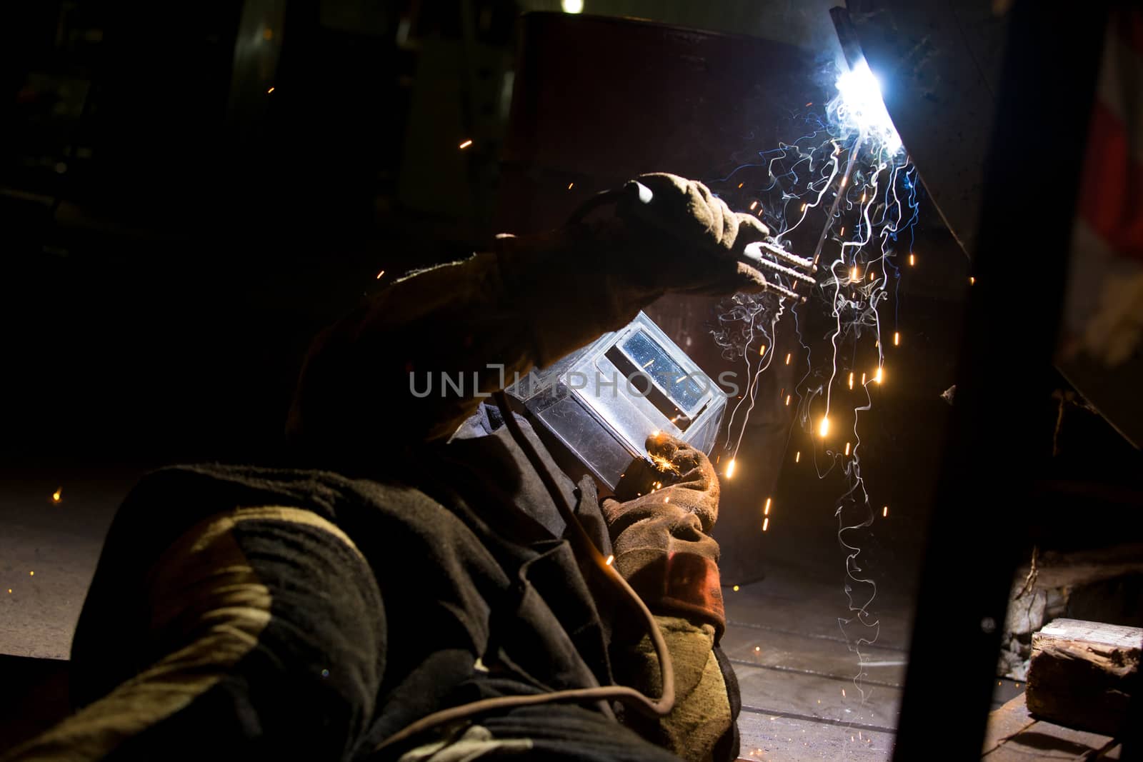 A welder is welding a metal pipe with electric welding.