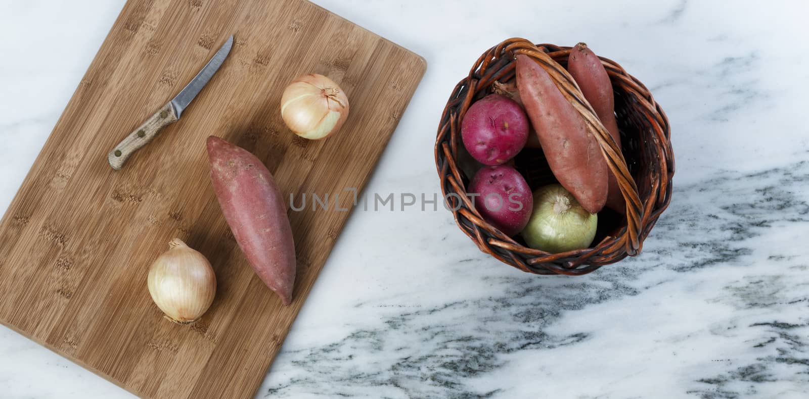 Cutting board with basket of organic raw vegetables to prepare for cooking