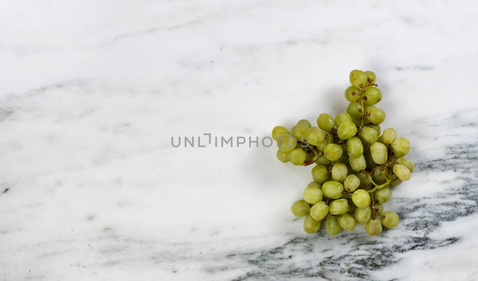 Fresh organic raw grapes on marble stone table in overhead view 