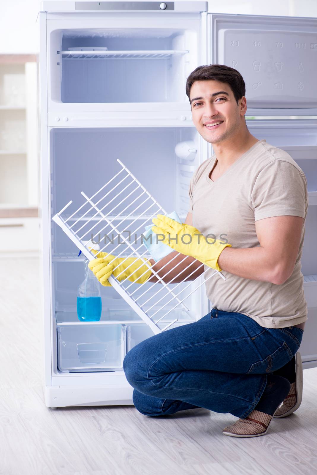 Man cleaning fridge in hygiene concept by Elnur