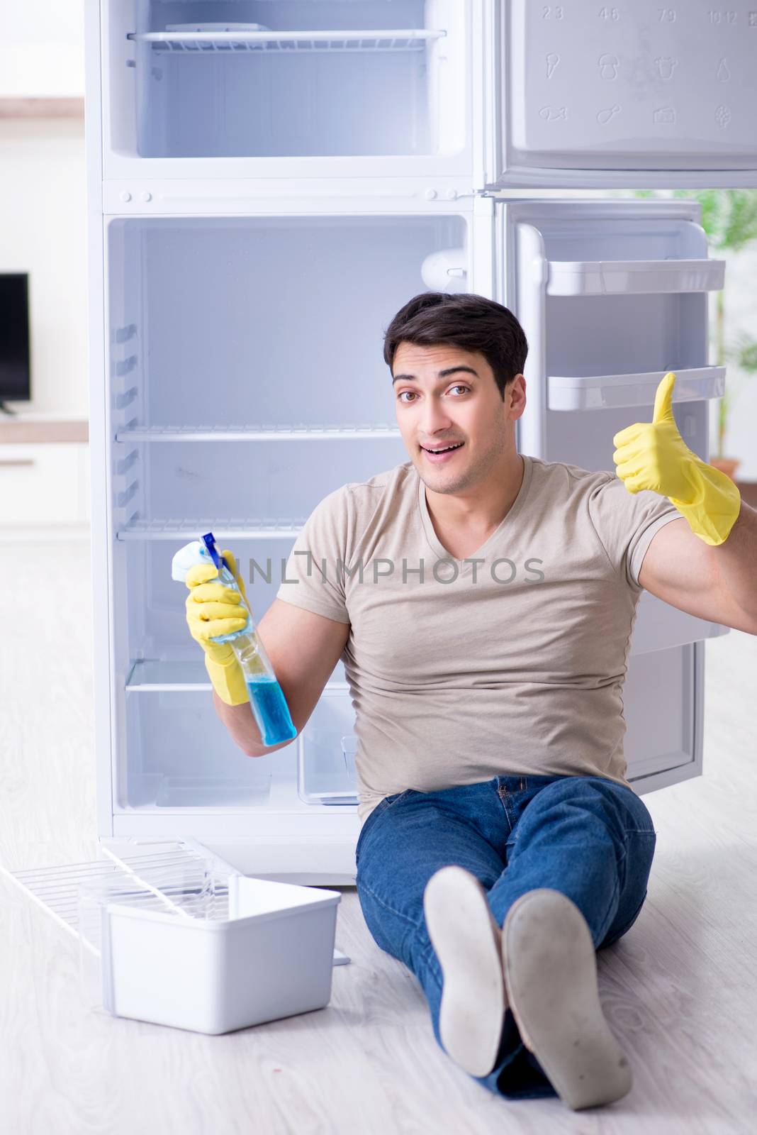 Man cleaning fridge in hygiene concept by Elnur