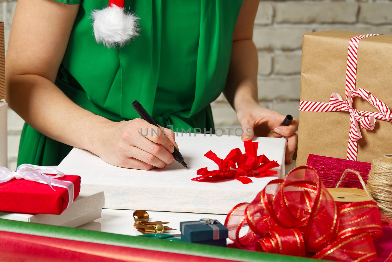 woman signs christmas gifts with a black pen. christmas gifts packing service concept